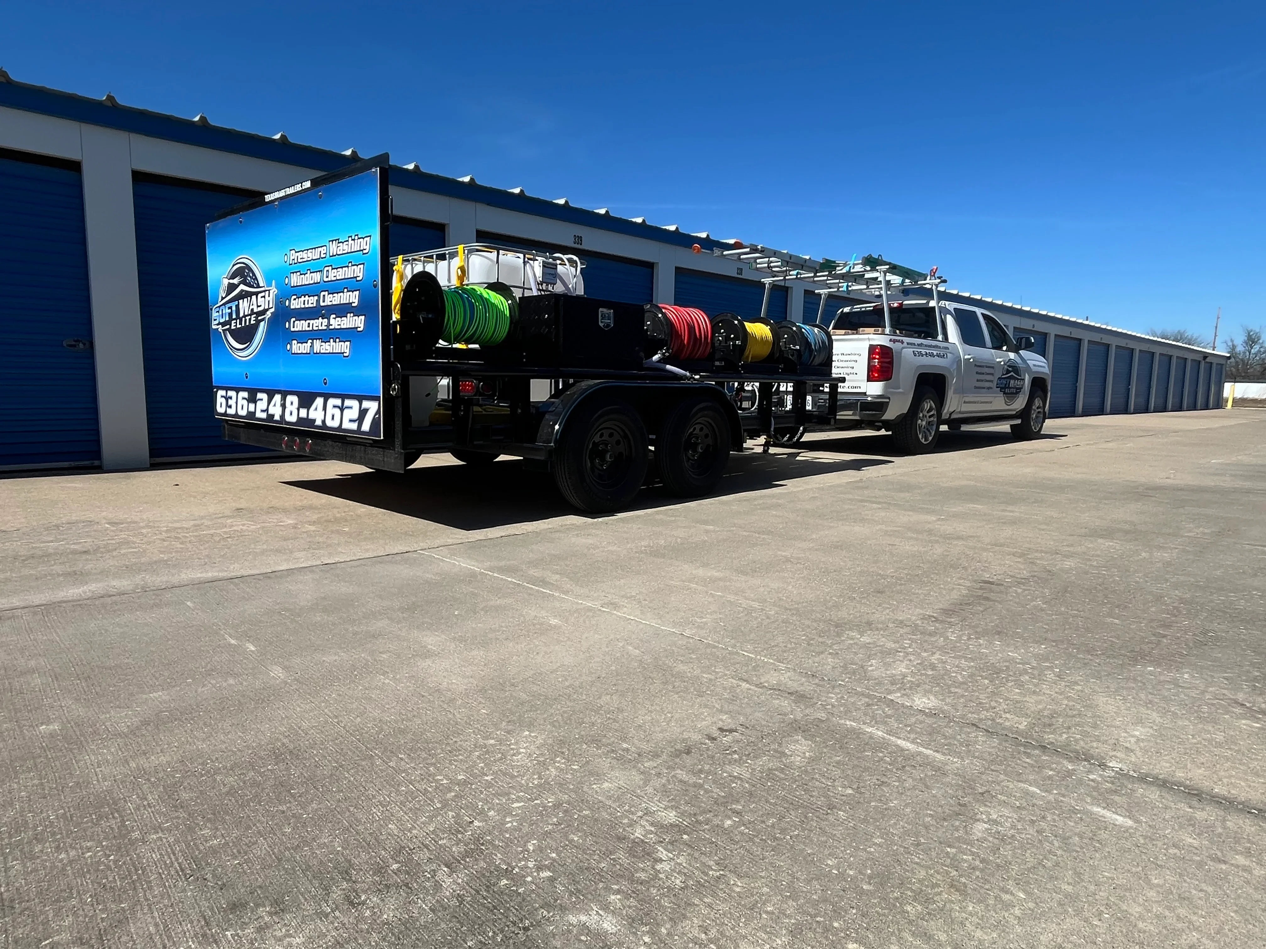 Pressure washing service truck with color-coded hose reels at commercial facility