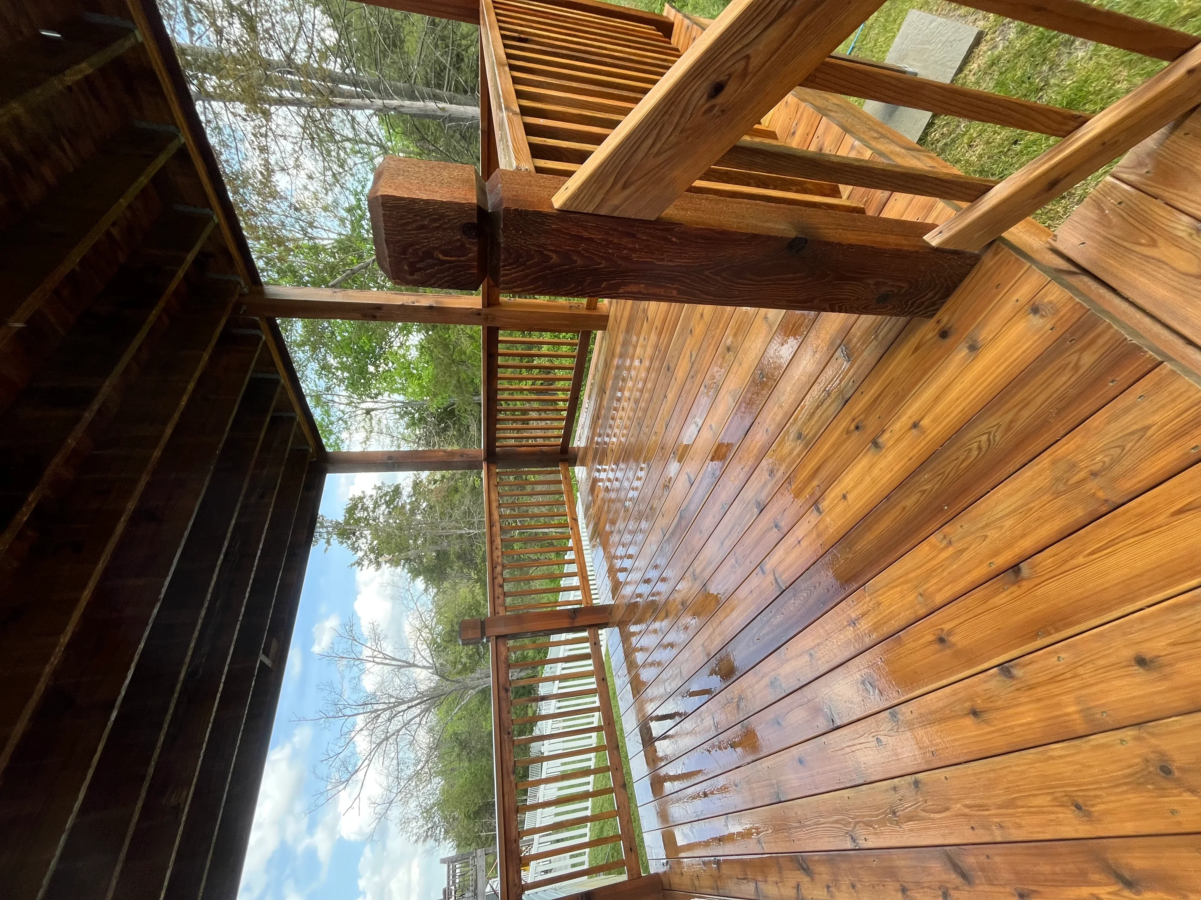 Clean wooden deck with pergola and multi-level construction overlooking wooded landscape