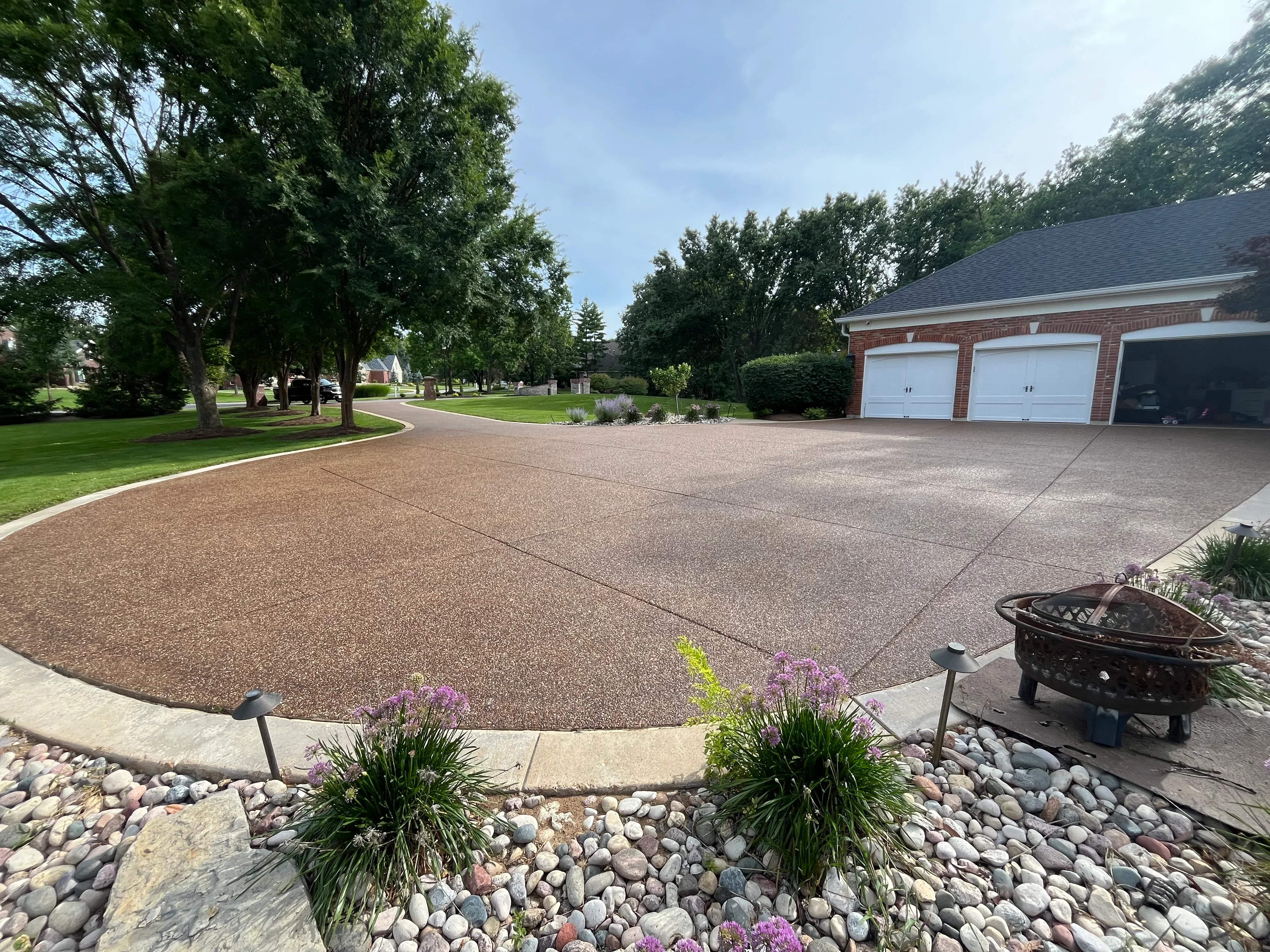 Clean sealed driveway with decorative concrete border and river rock landscaping