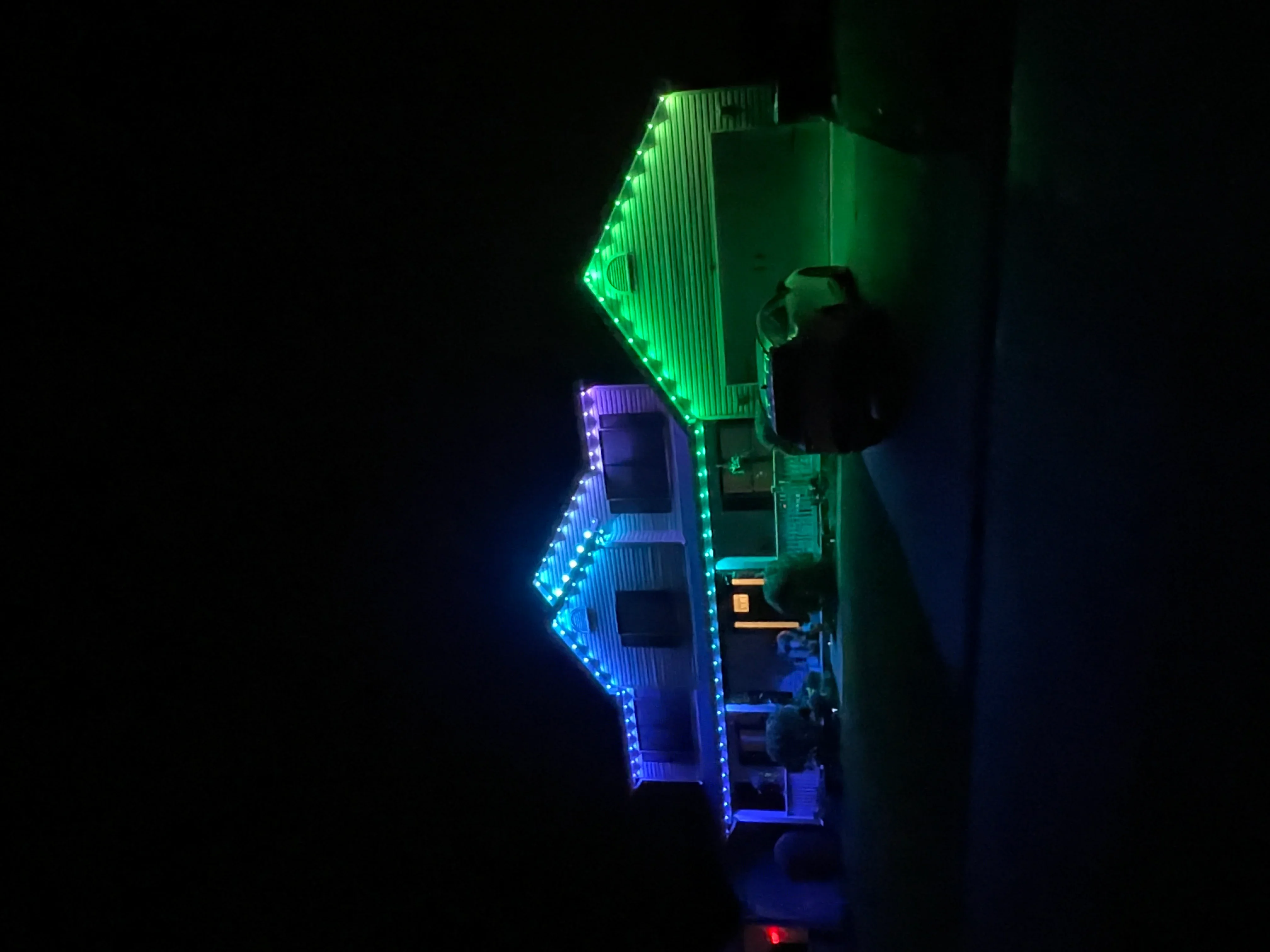 Green and blue LED holiday lights outlining a residential building at night