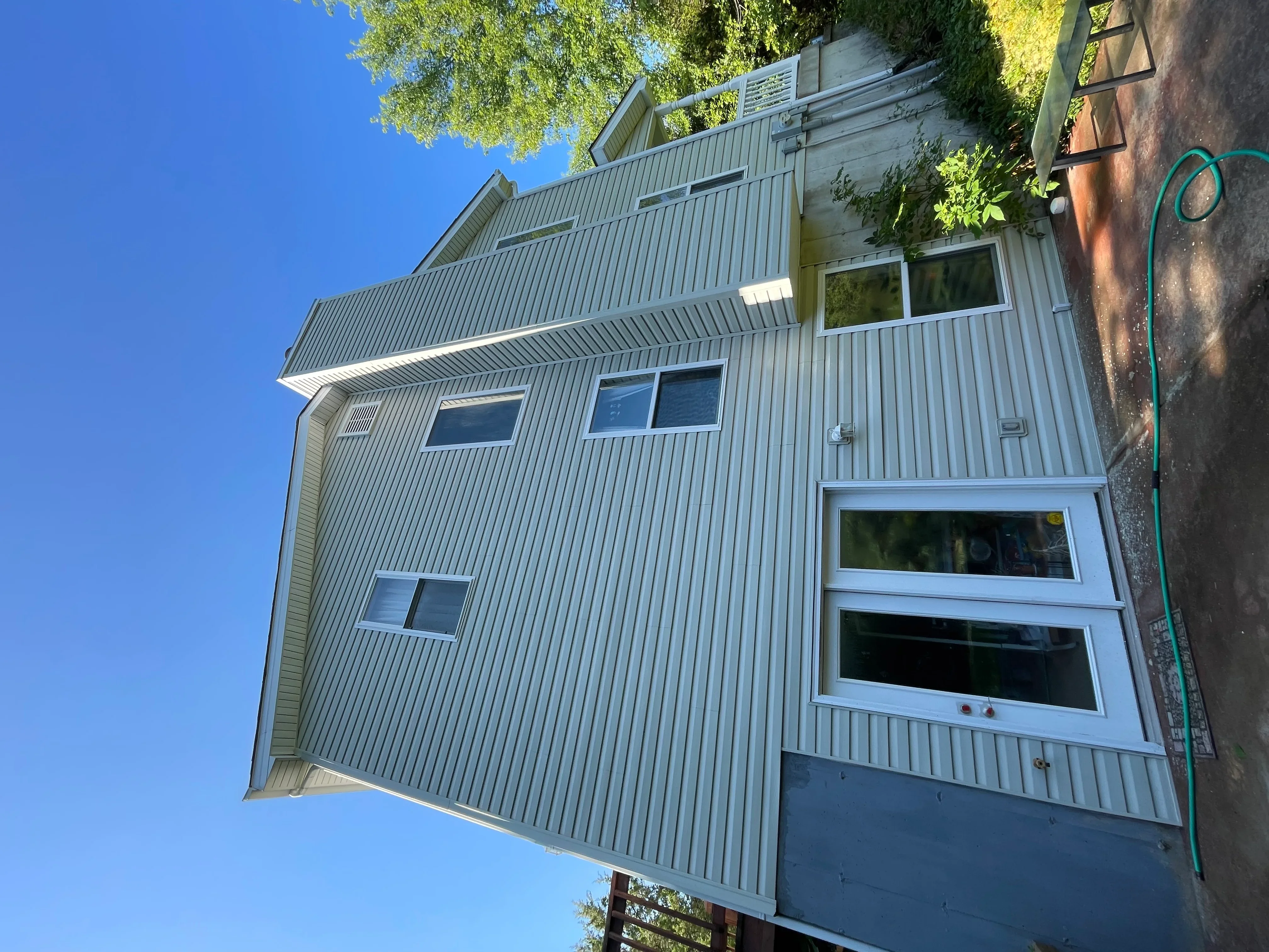 Clean metal-sided house with bright windows after professional soft wash cleaning