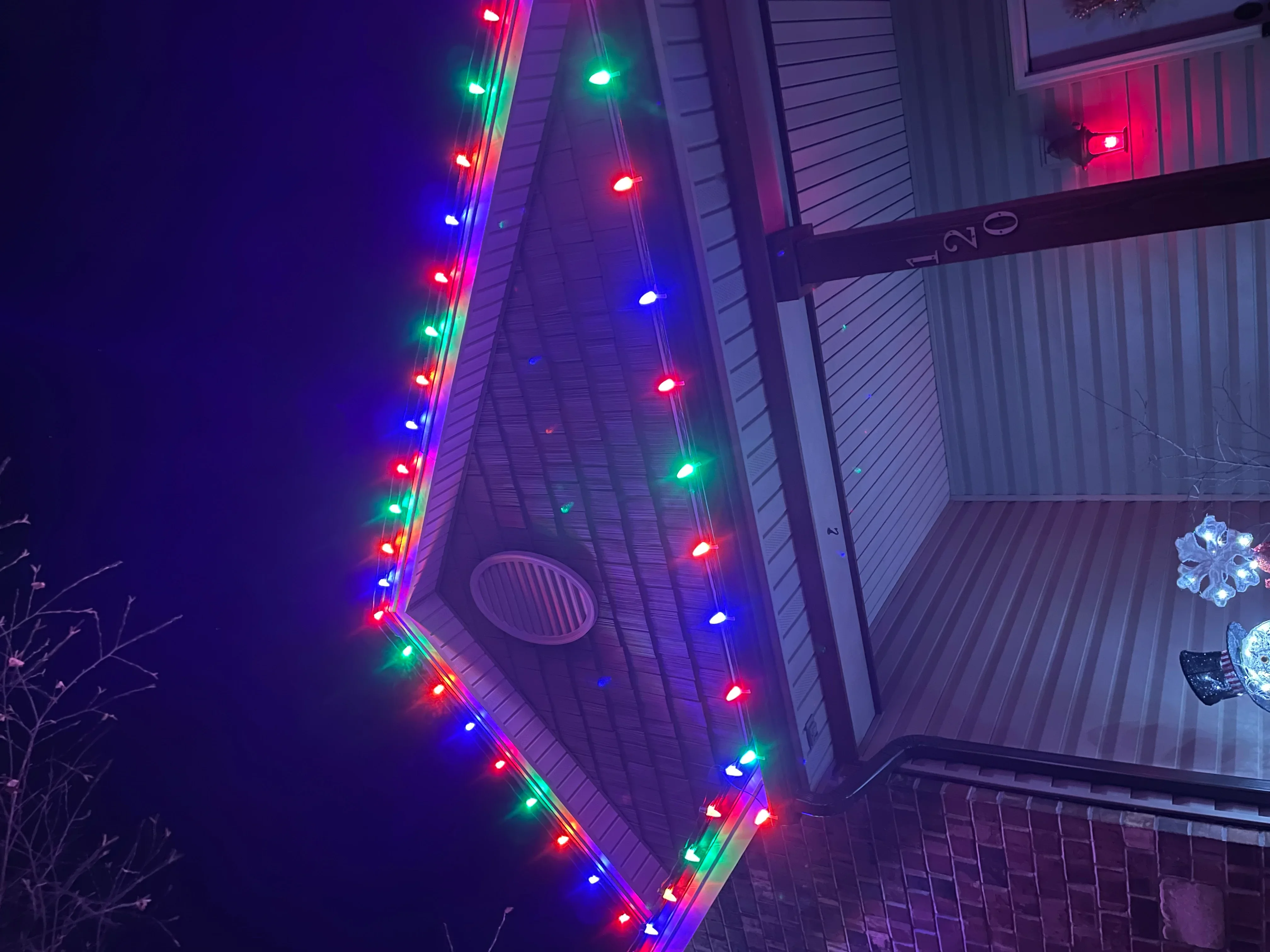 Multi-color LED holiday lights installed along residential roofline at night