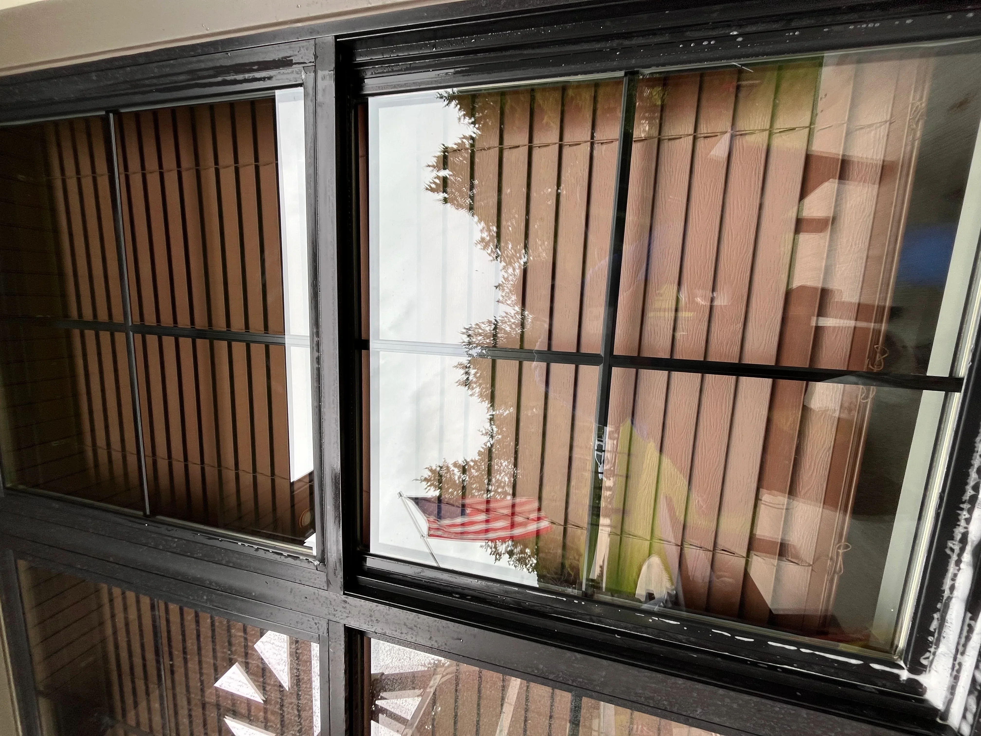Clean multi-pane residential windows with black frames overlooking brick home exterior