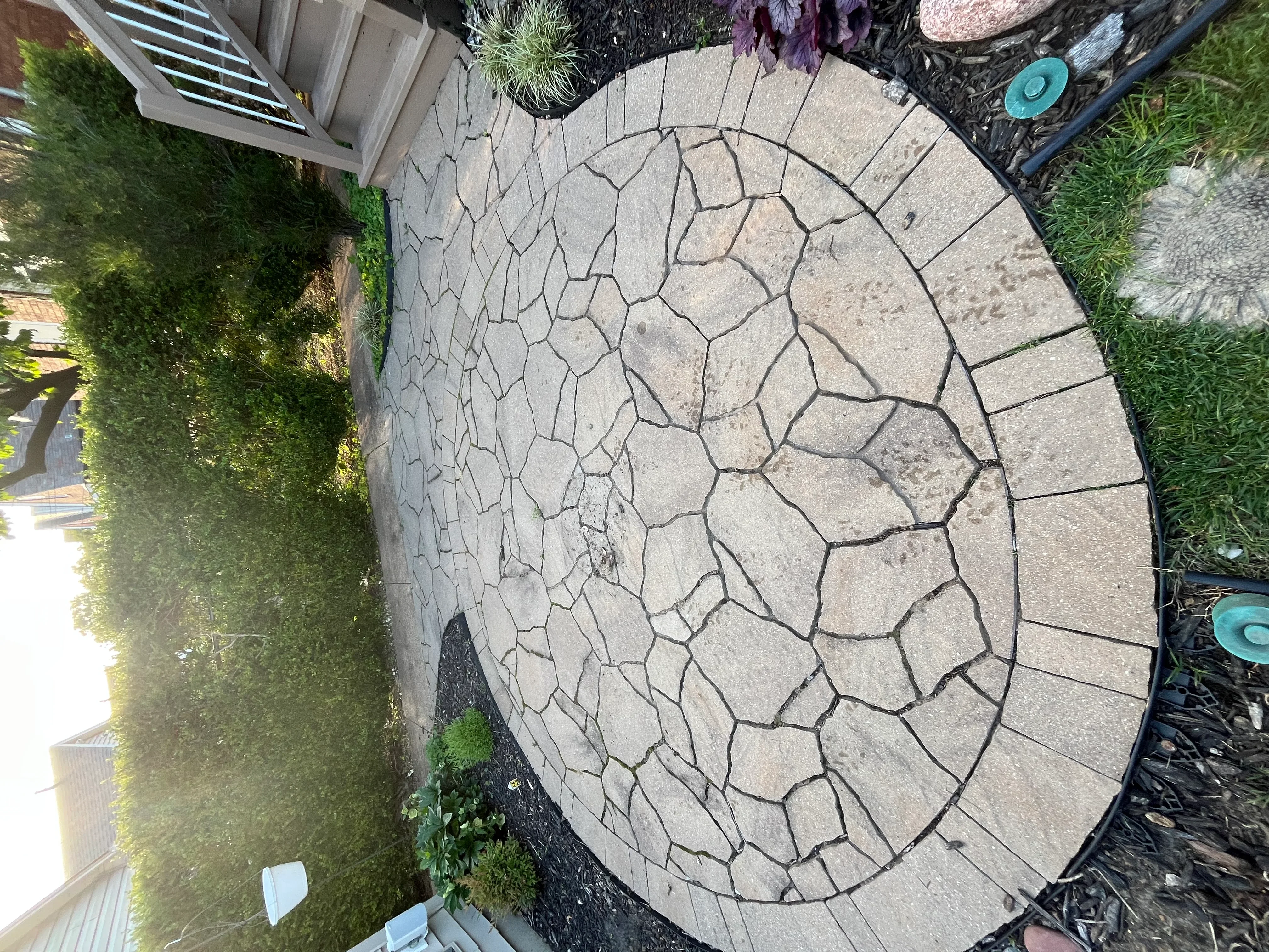 Circular paver patio after pressure washing, showing clean light gray stones with defined joints