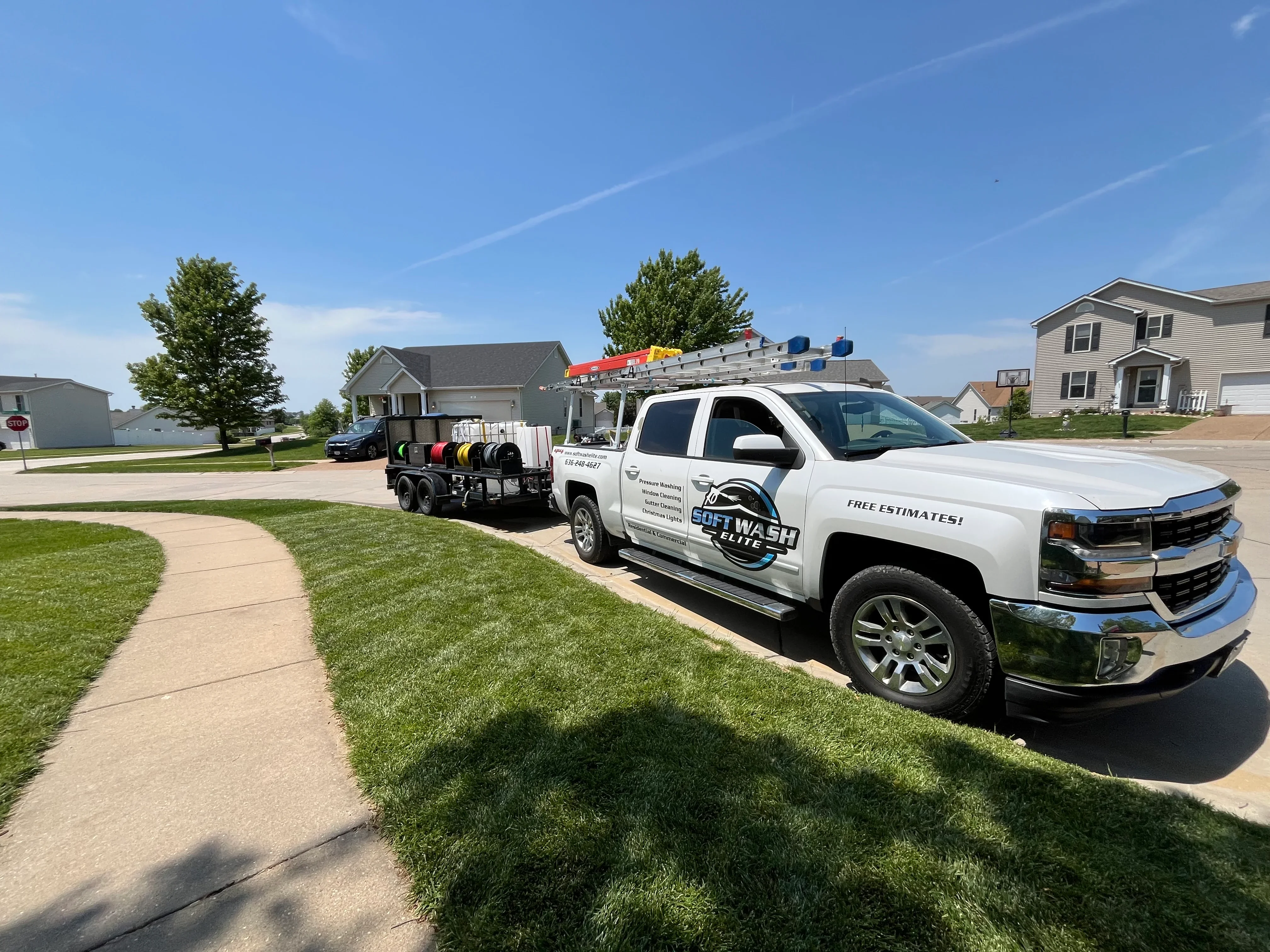 White Chevrolet service truck with soft wash equipment and trailer in residential driveway