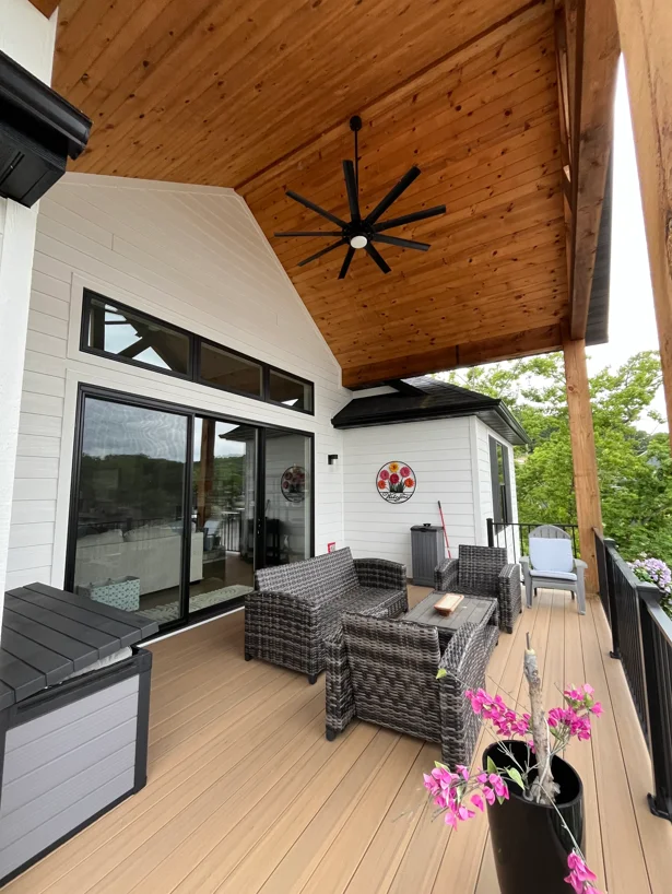 Clean composite deck with pressure-washed white siding and wood ceiling under covered patio