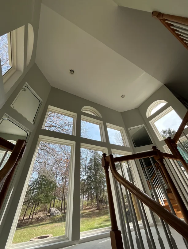Clean multi-panel windows in bright interior with wood railings and vaulted ceiling