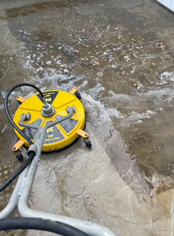 Rotary surface cleaner on wet concrete during pressure washing treatment
