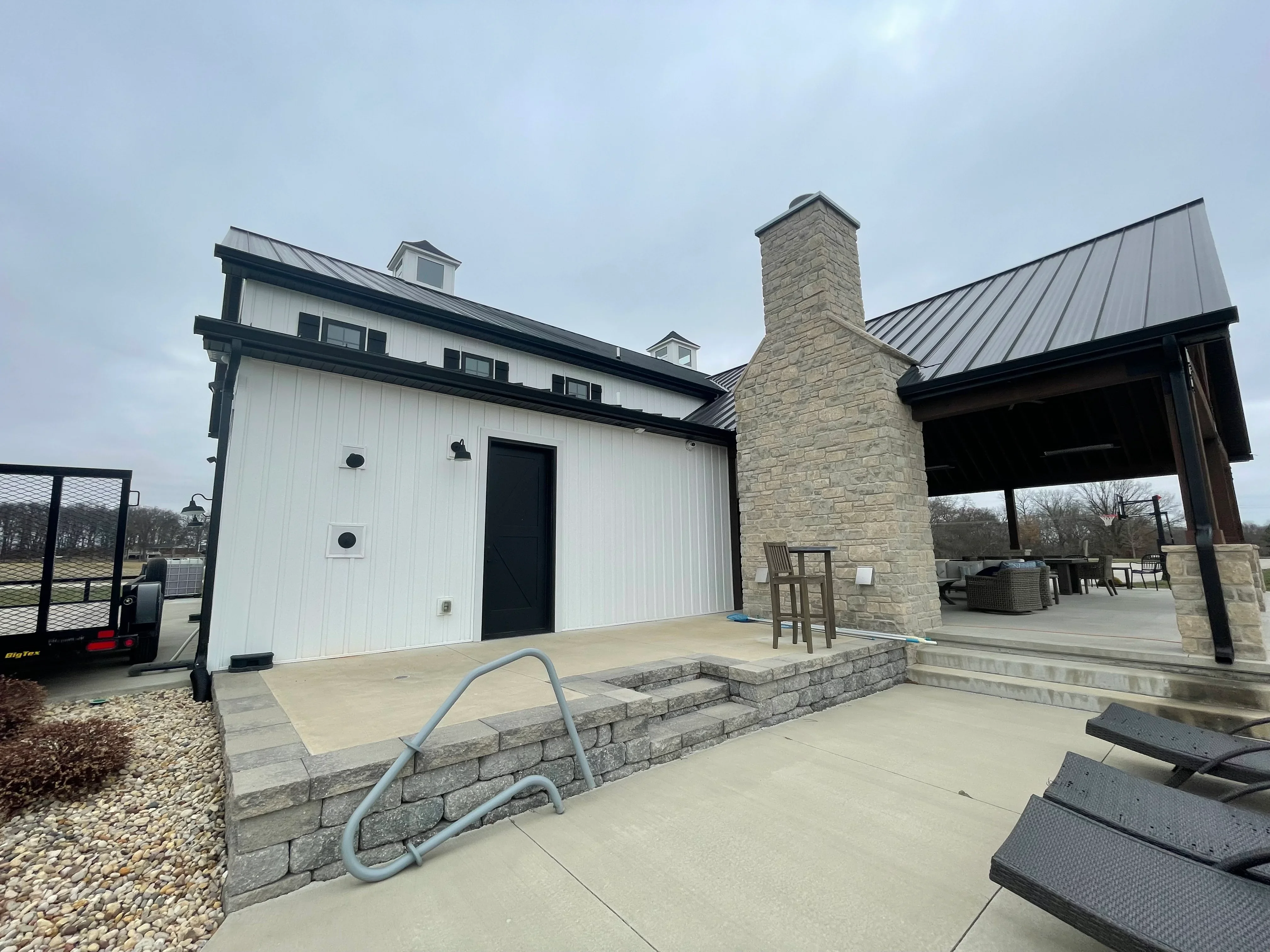 Modern home with white siding, stone chimney, and cleaned concrete patio areas