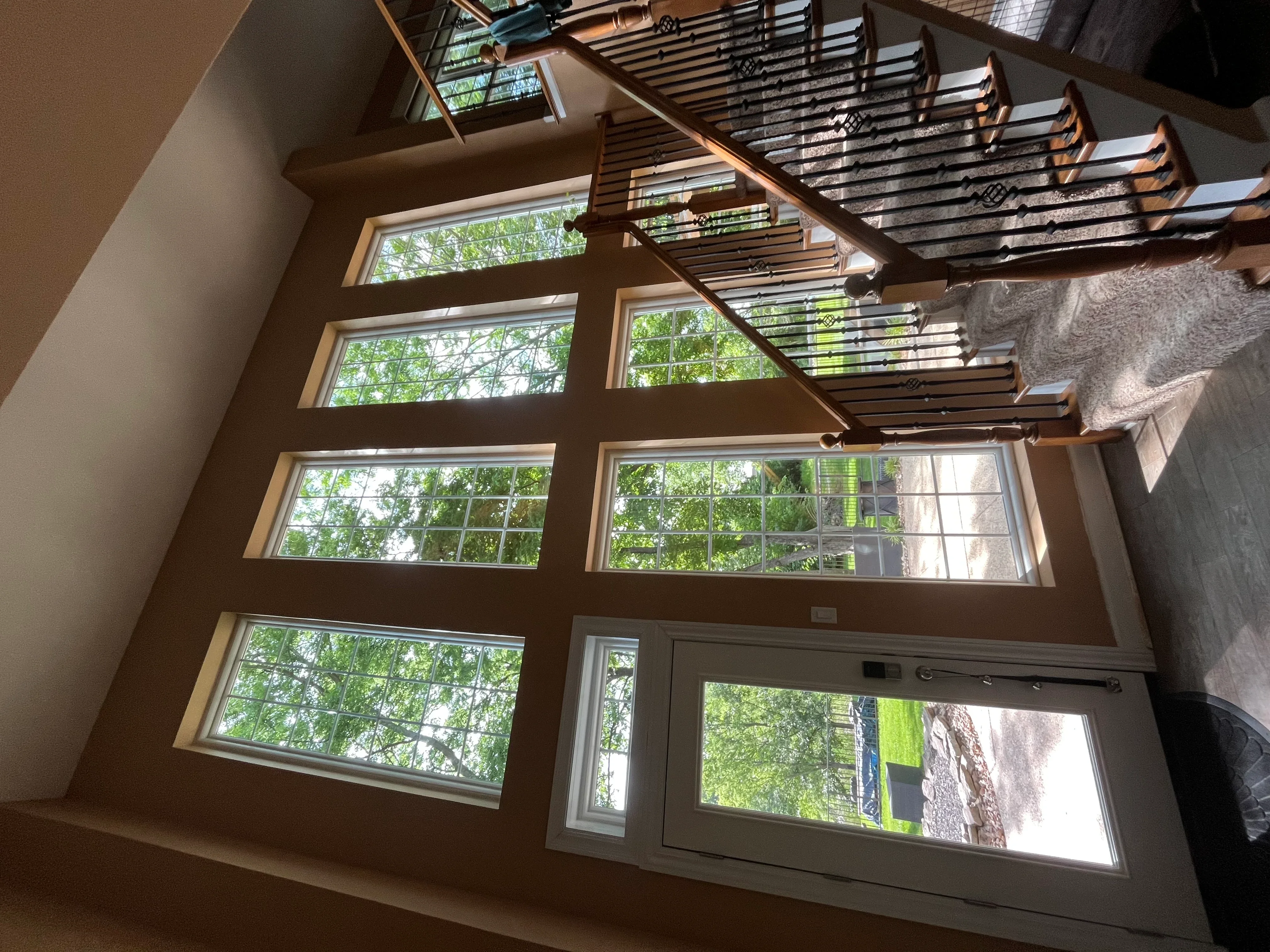 Clean residential windows with wood frames and staircase railing in bright interior space