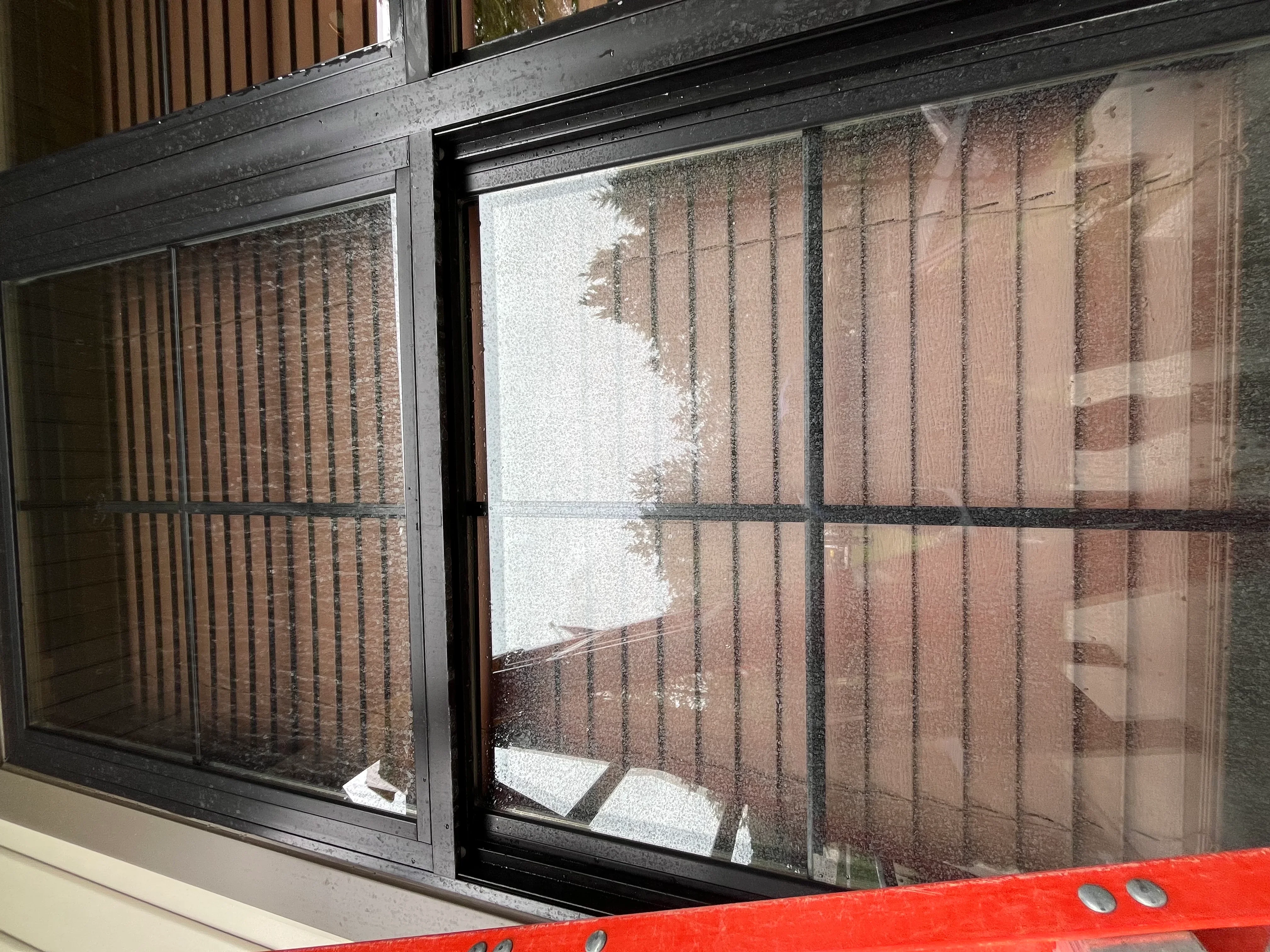 Clean sliding glass doors with black frames showing brick exterior reflection