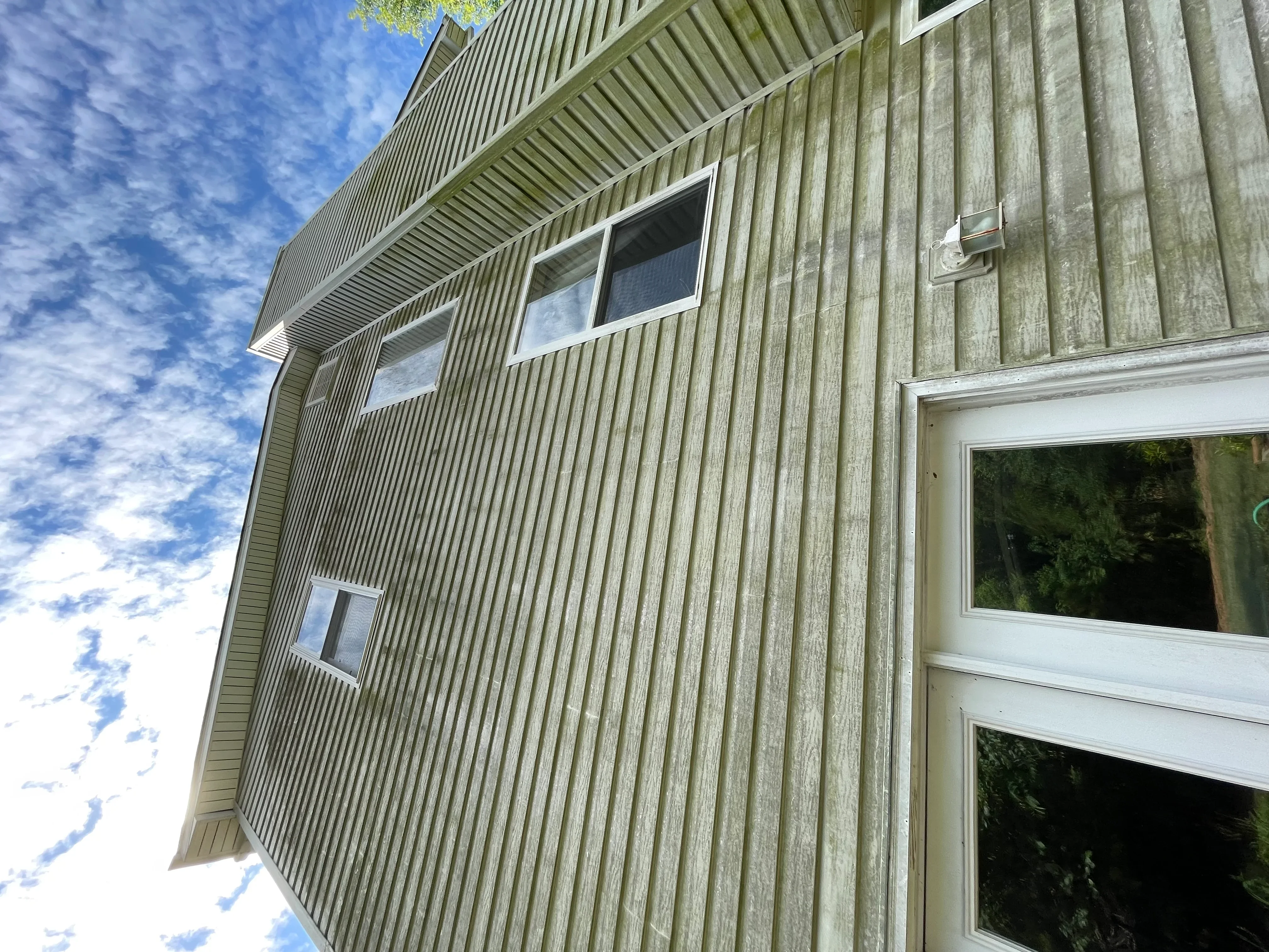 Clean metal corrugated siding on residential home with white trim and windows