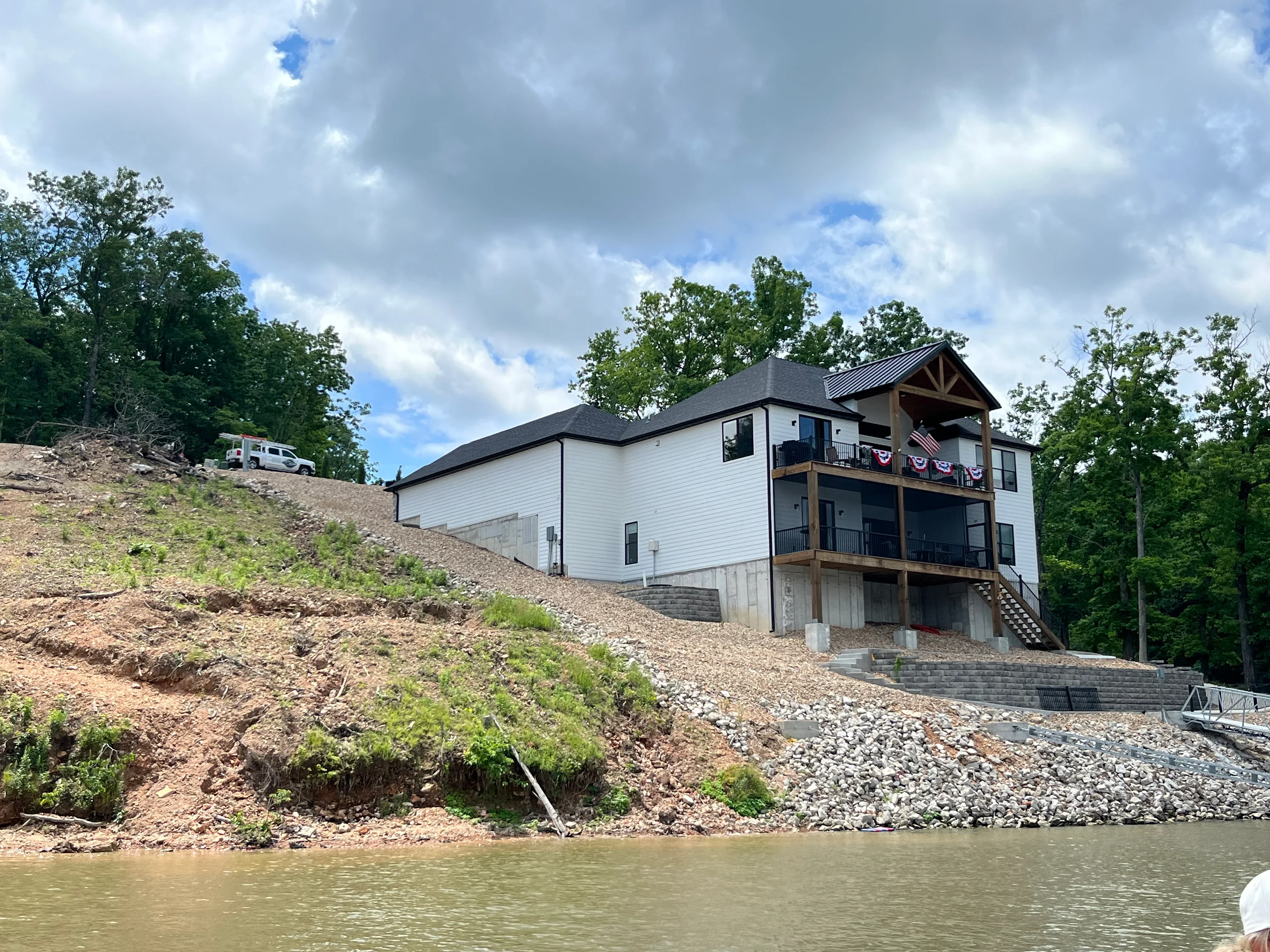 White two-story home with timber accents on hillside overlooking river after pressure washing