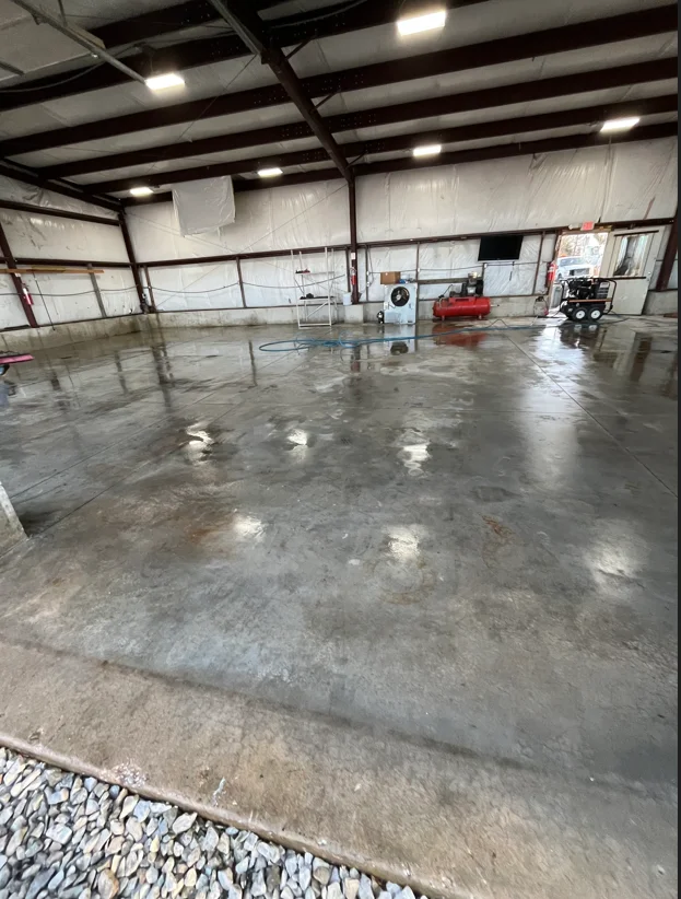 Pressure-washed concrete warehouse floor with industrial steel beam ceiling and equipment