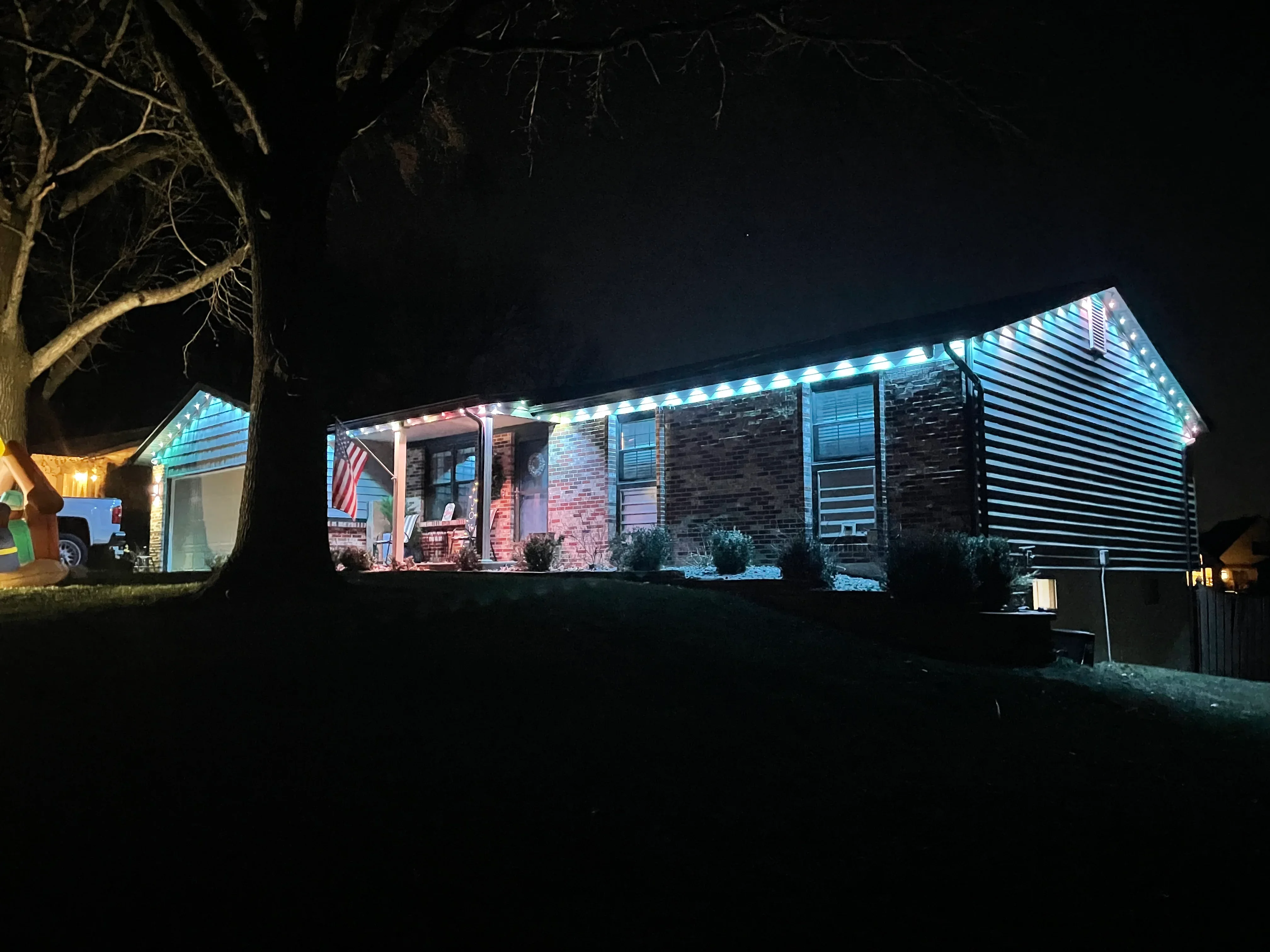 Brick home at night with LED holiday lighting along roofline and soffit