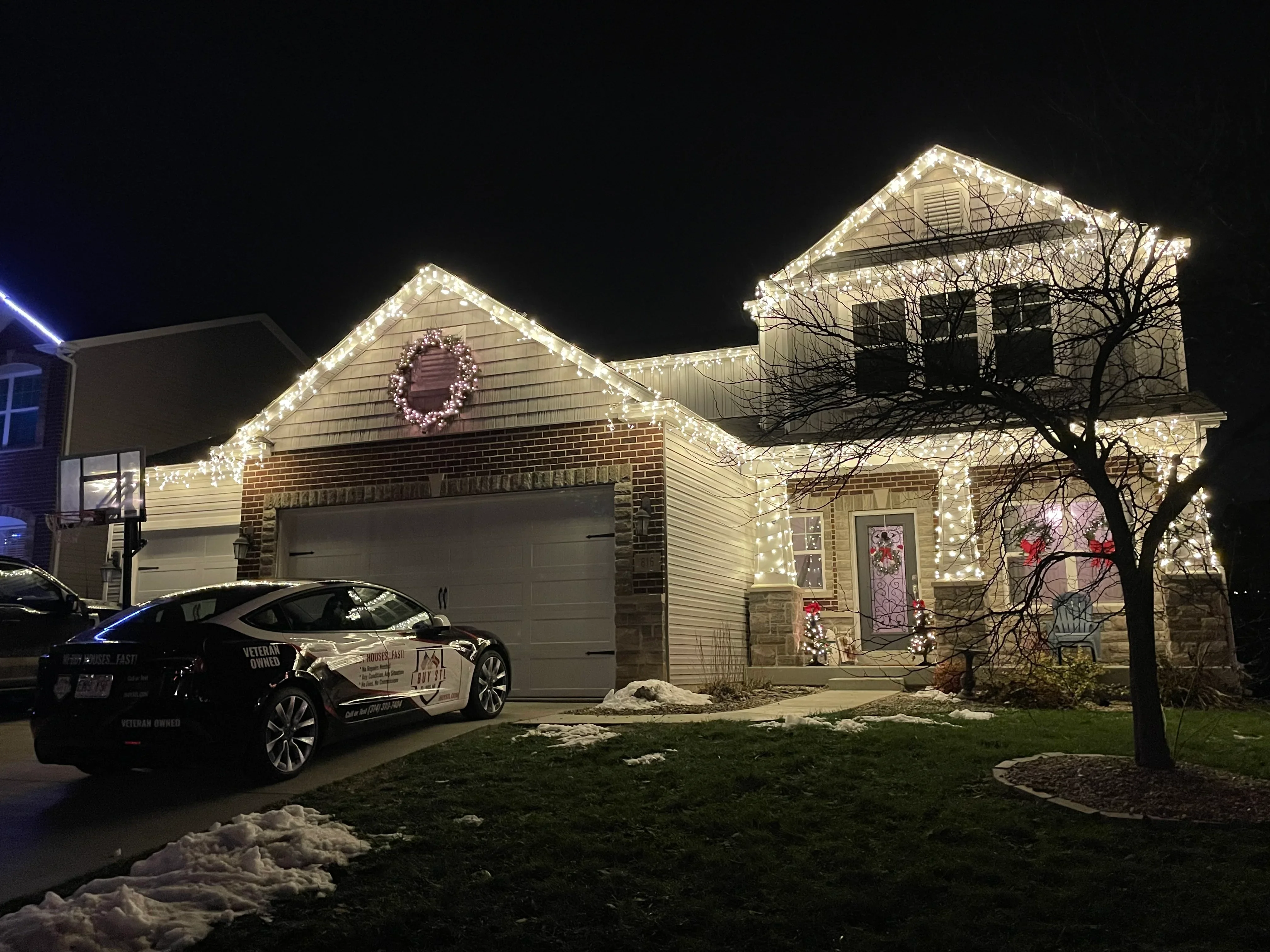 Two-story home at night with warm white LED lights outlining roofline and gables