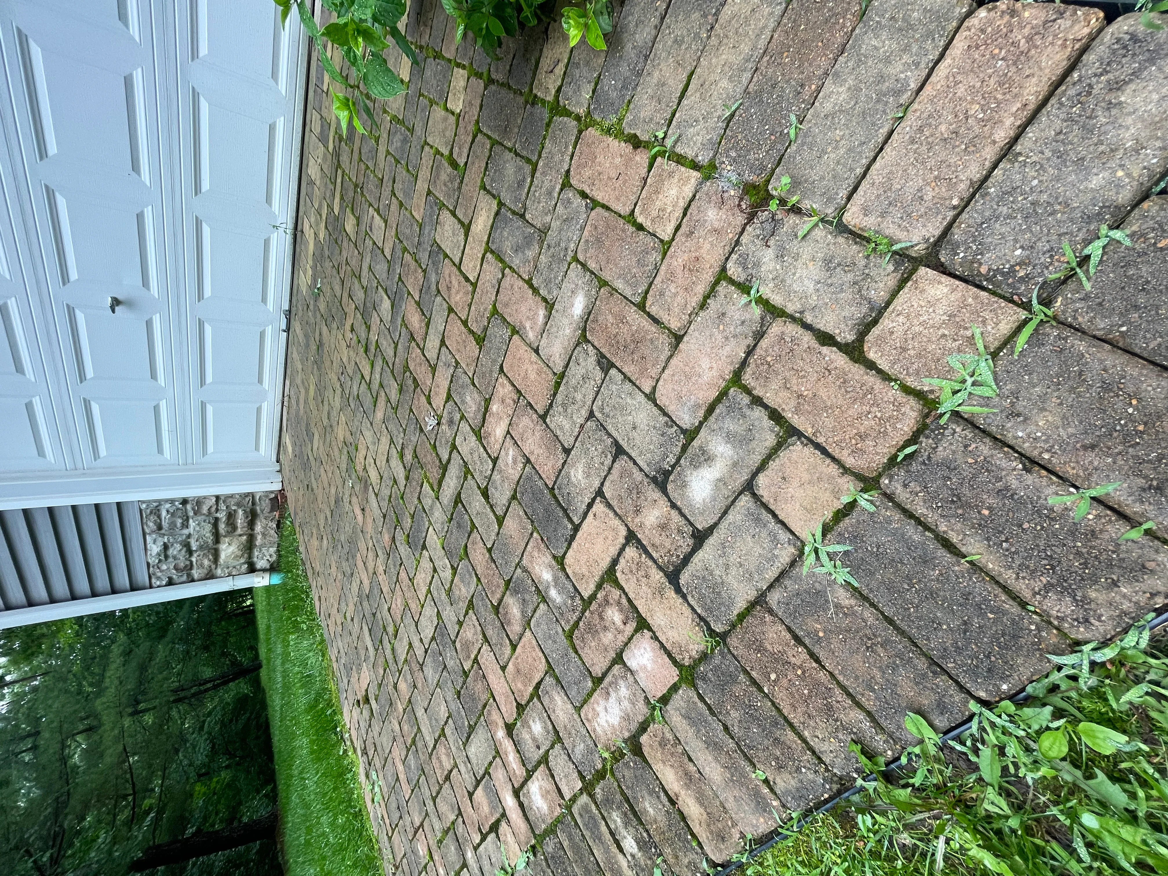Clean brick patio with herringbone pattern next to white garage door