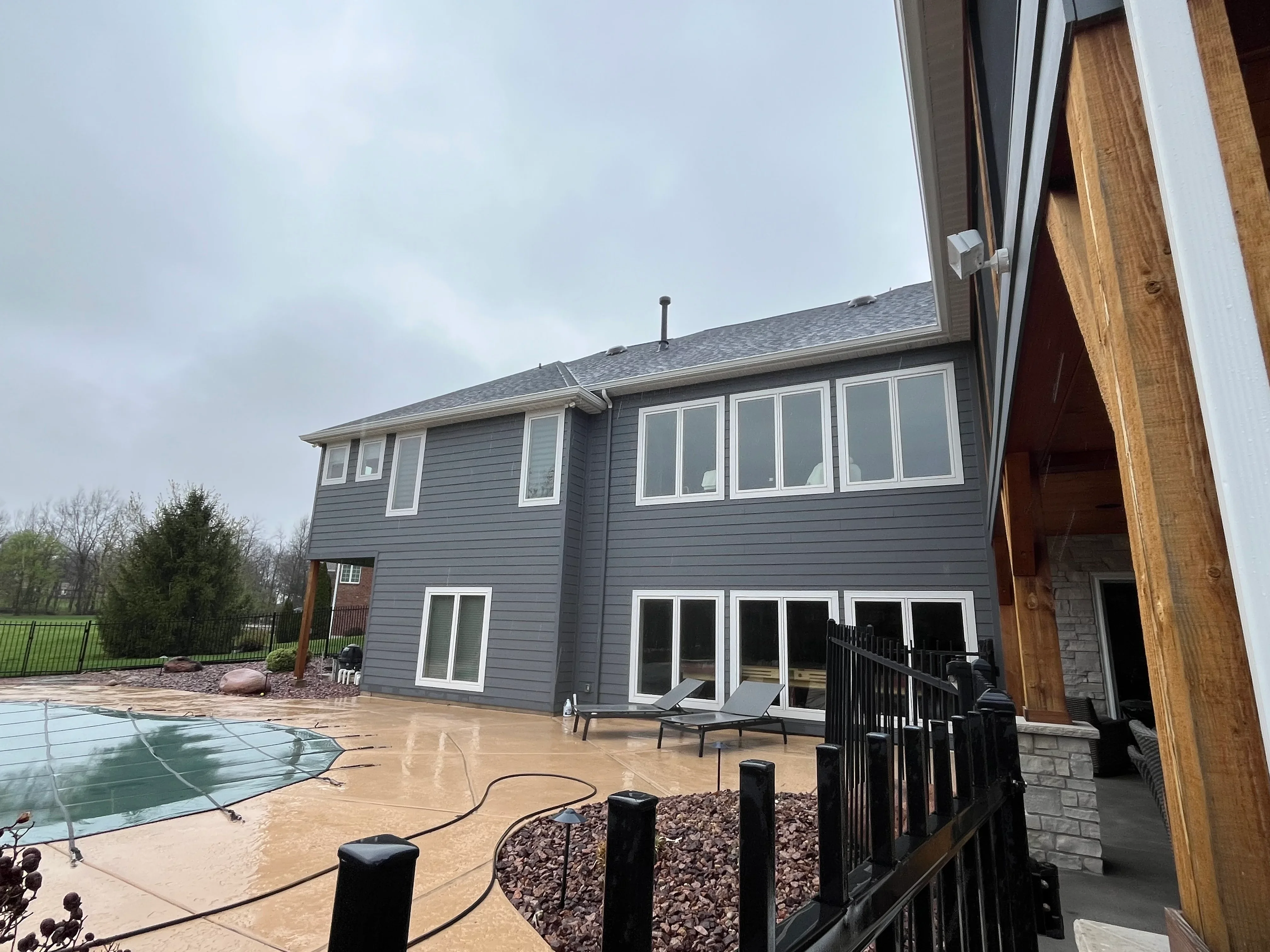 Gray two-story home with cleaned patio, pool, and black metal railing