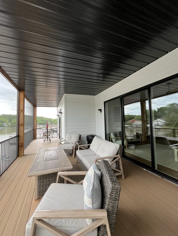 Clean composite deck with white patio furniture, metal railings, and pressure-washed siding overlooking landscape
