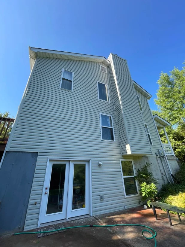 Light blue vinyl siding home cleaned with soft wash technique, three-story residential exterior