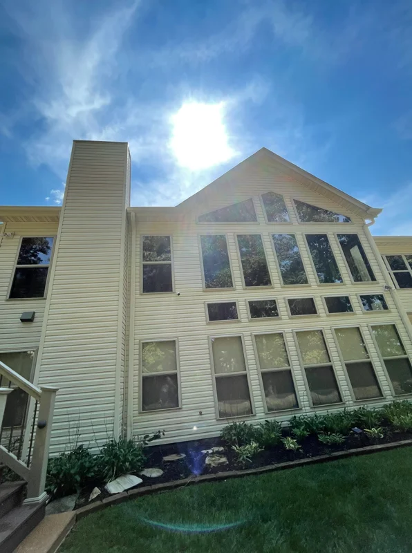 Two-story white vinyl siding home with cleaned exterior and multi-pane windows