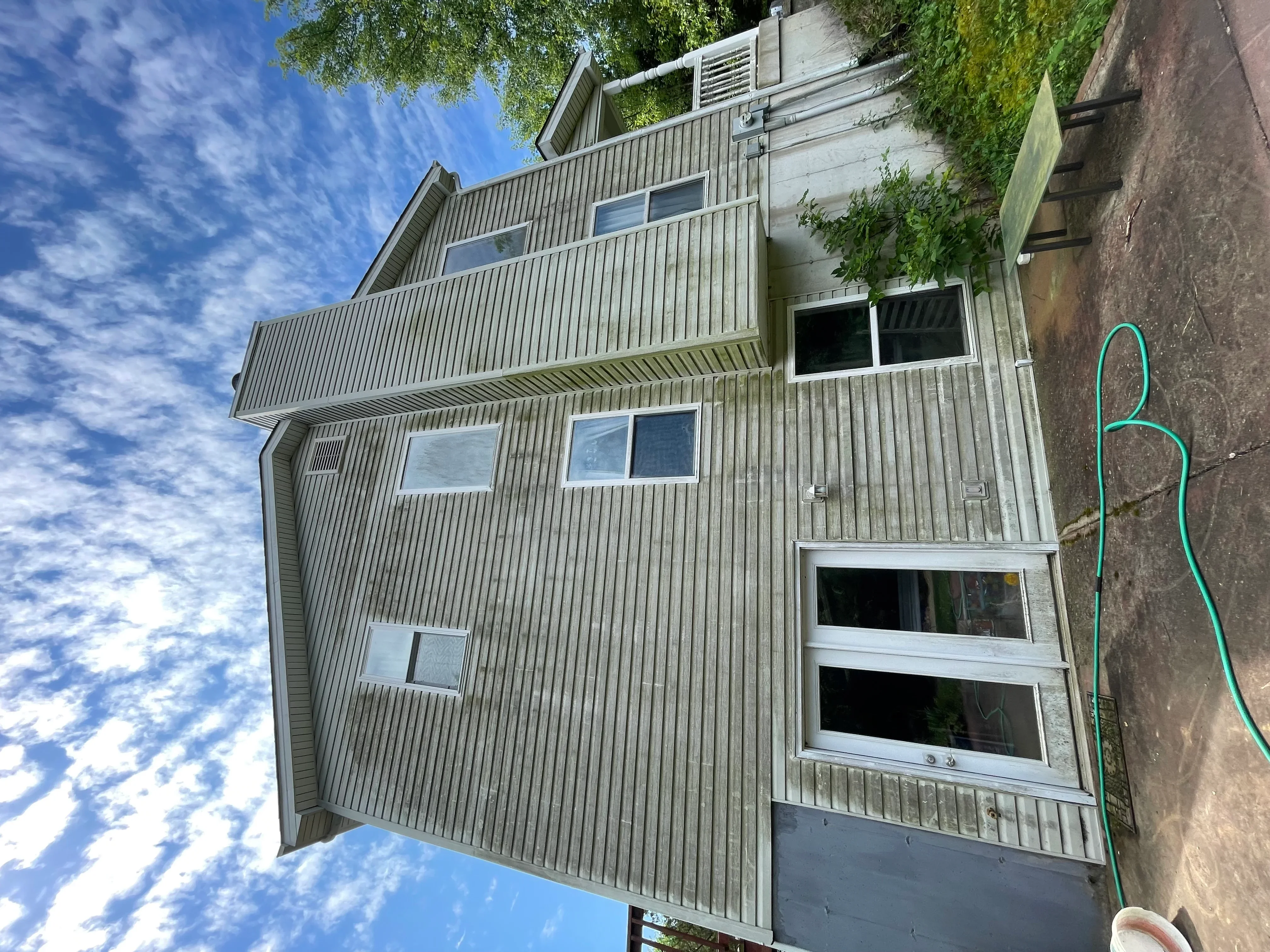 Two-story home with cleaned metal siding, bright windows, and deck after pressure washing service