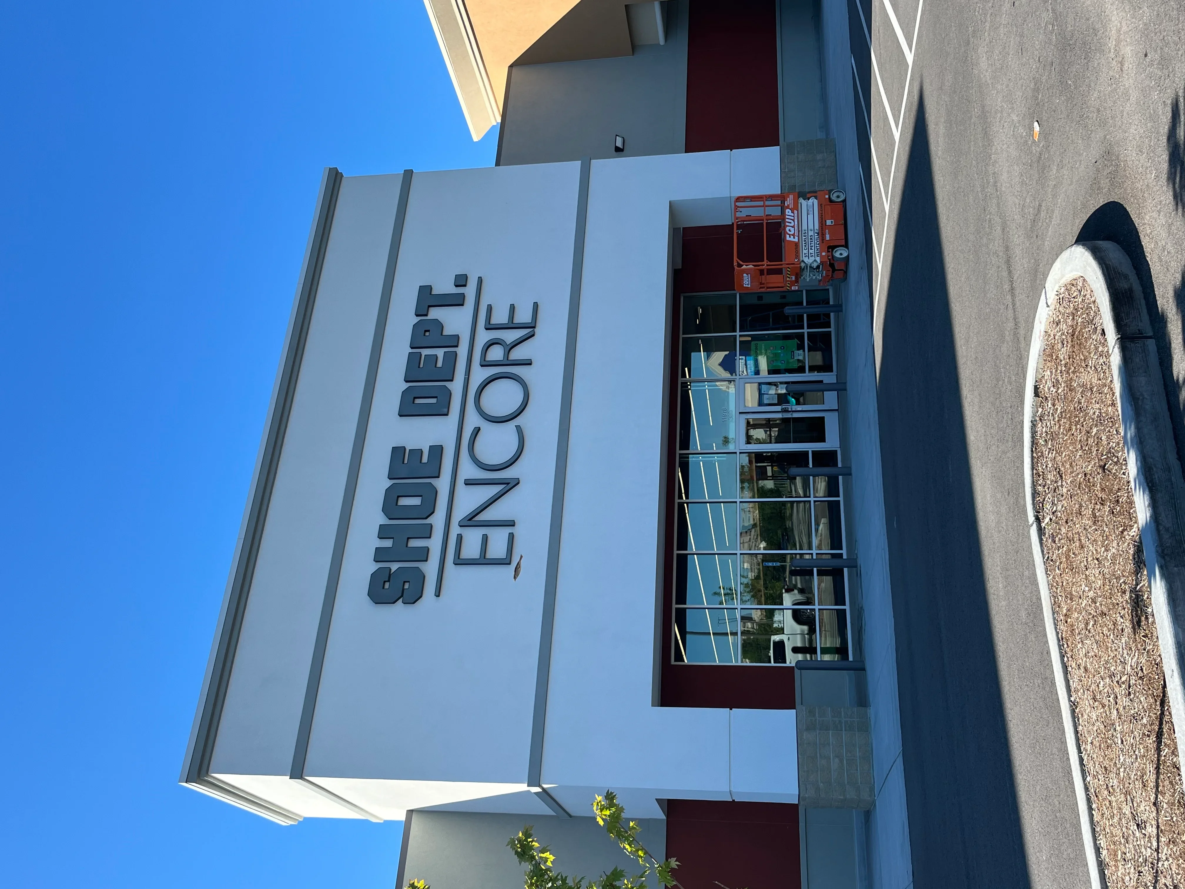 Clean light blue commercial building facade with dimensional lettering and storefront windows