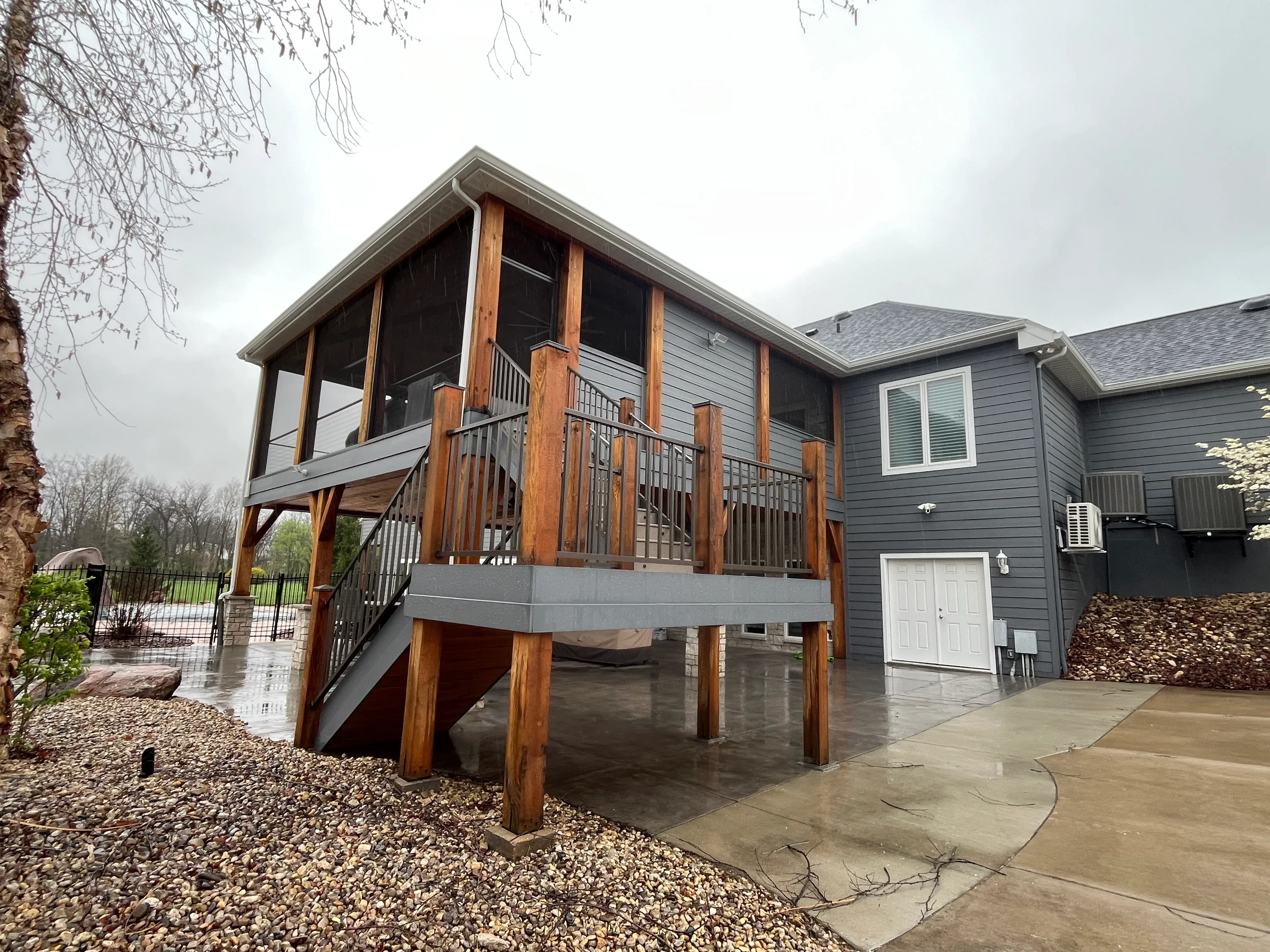 Clean elevated residential deck with wood posts and metal railings next to gray house