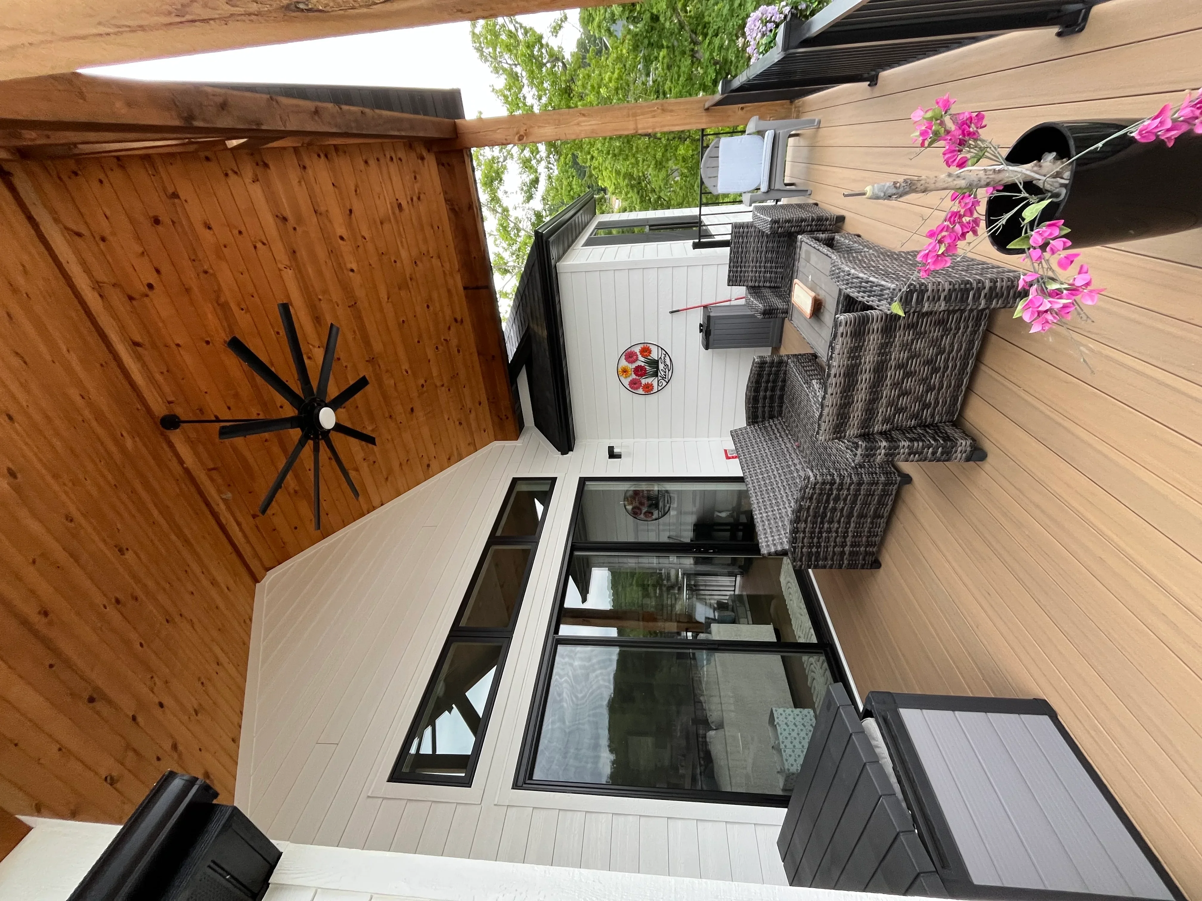 Clean composite deck with wooden fence, patio furniture, and flowering plants
