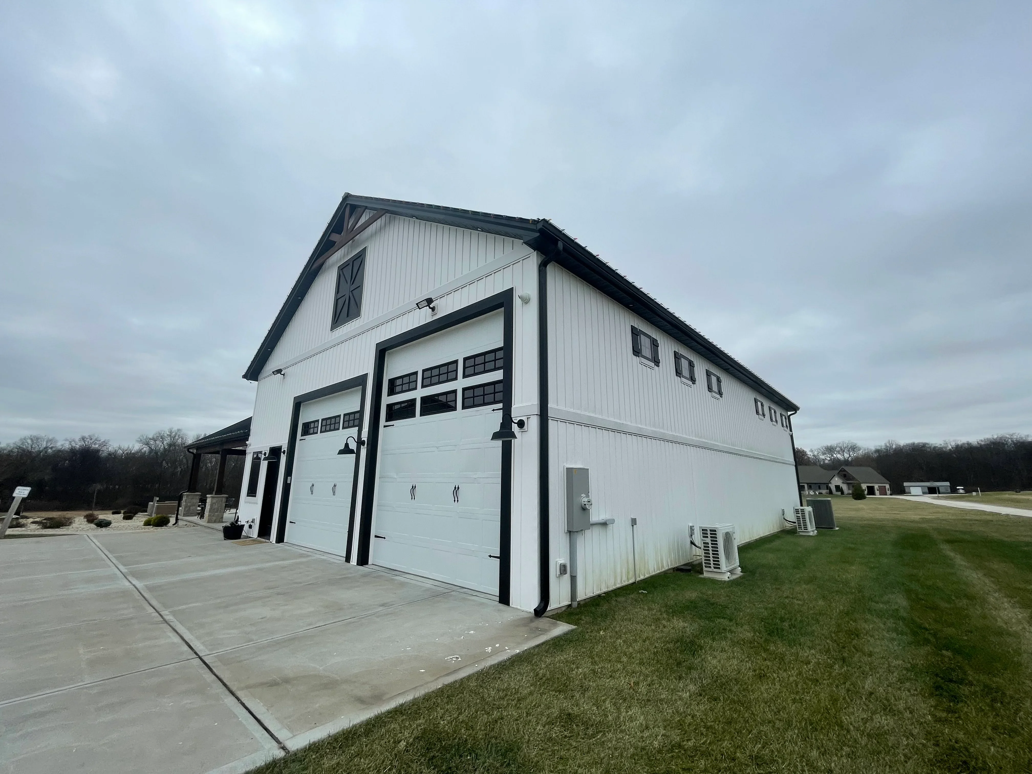 Clean white metal garage with black trim and white garage doors on concrete pad