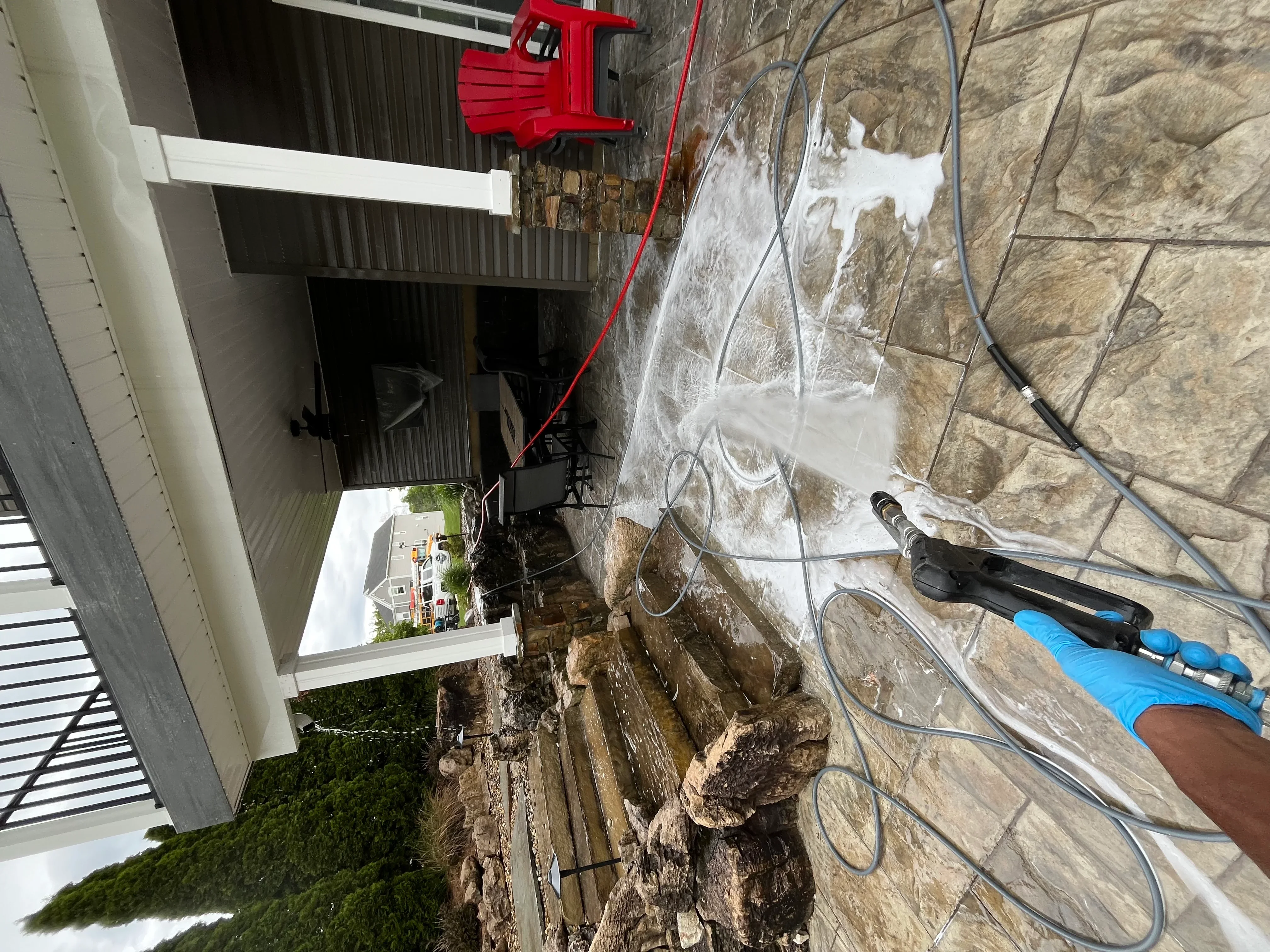 Stone facade being soft washed with low-pressure equipment and cleaning solution
