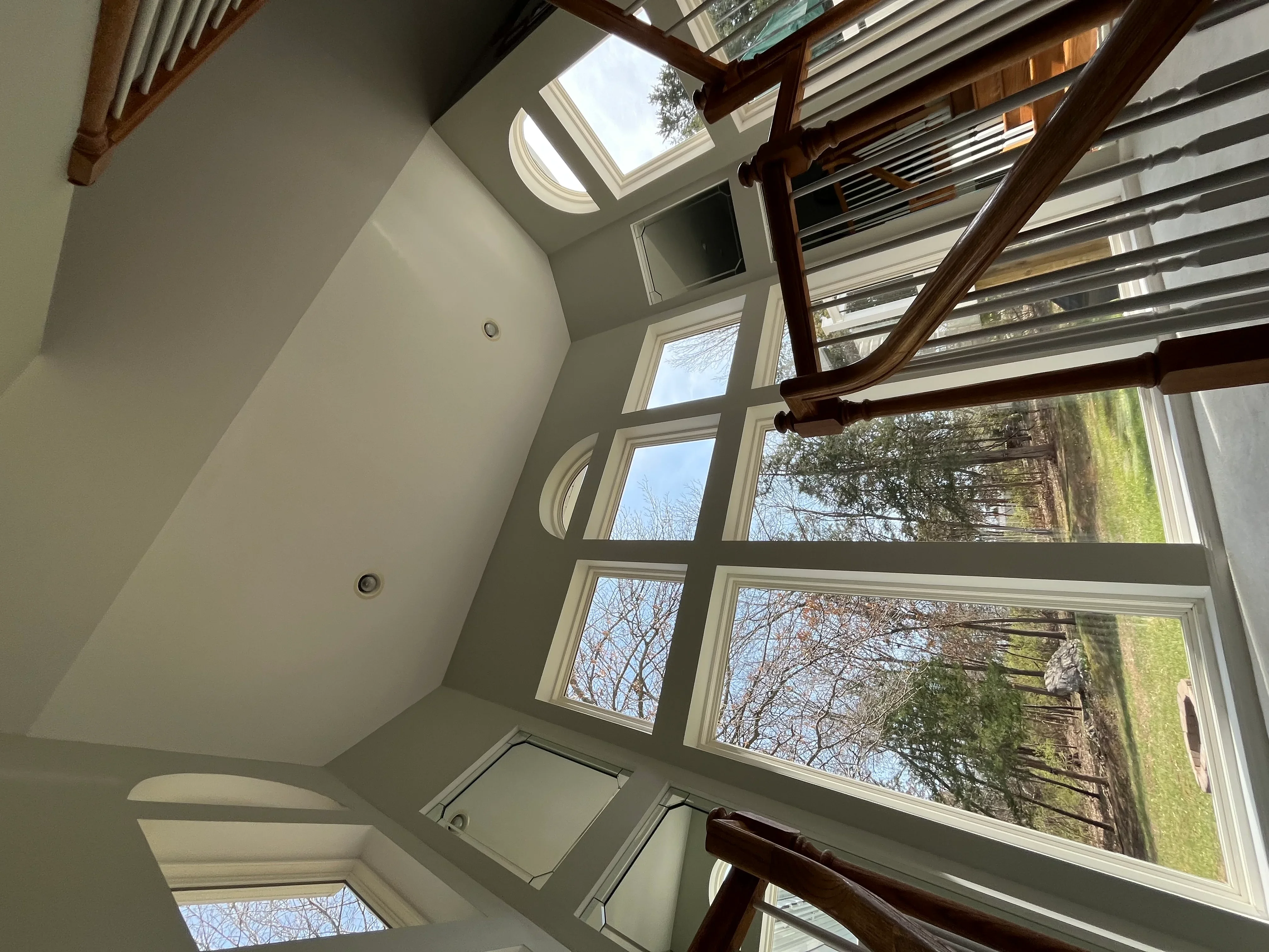 Clean sunroom windows with wood beams and skylights overlooking outdoor landscape