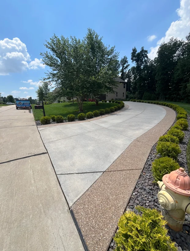 Pressure-washed concrete driveway and entryway with decorative stone borders and landscaping